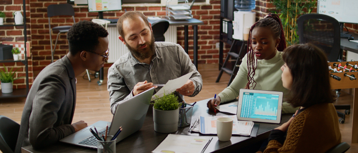 feature image for ServiceNow performance analytics blog. Visual of 3 people sitting at a desk and talking to each other.