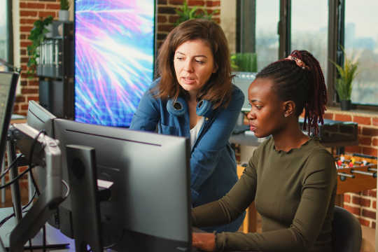 Visual of two women looking at a monitor screen. Used as a visual for ServiceNow quality blog