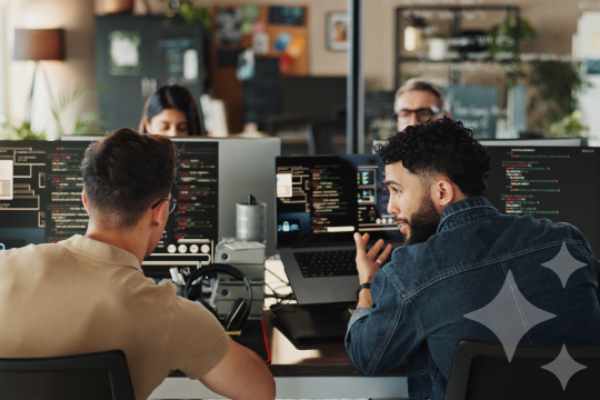 Image of two male colleagues working together in front of 2 laptop screens. Visual used as a feature image for ServiceNow Now Assist blog.